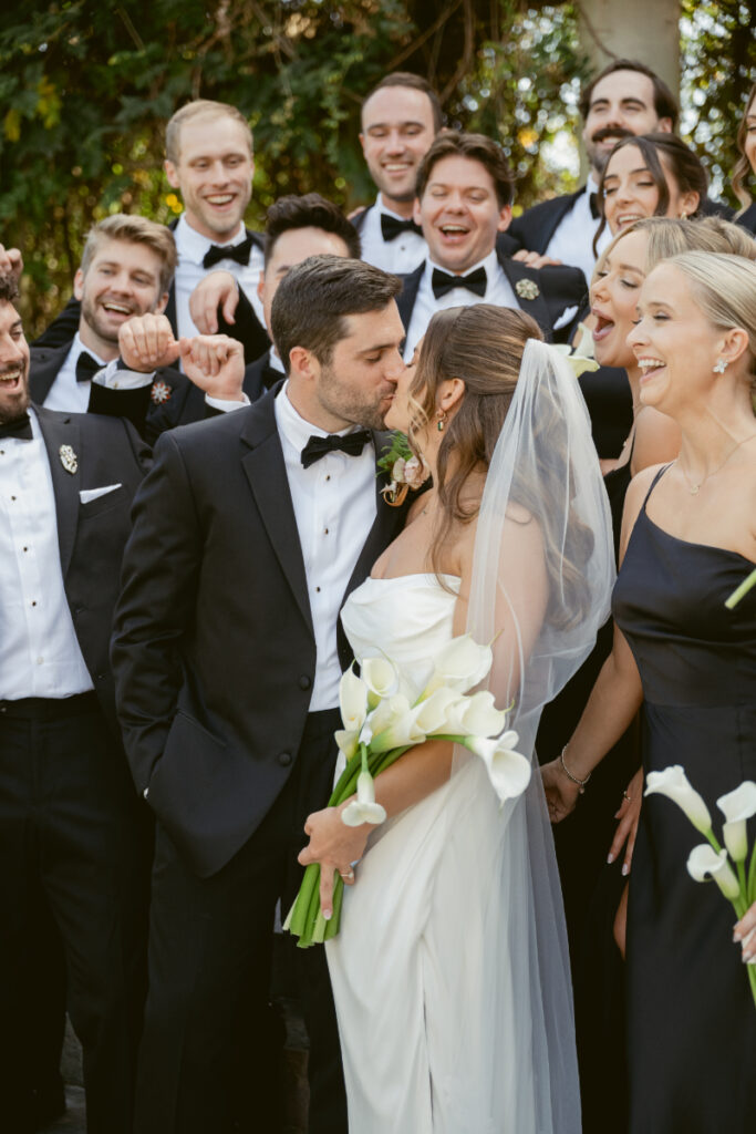 Bride and groom kiss surrounded by bridal party at elegant Laurel Court wedding in Cincinnati.