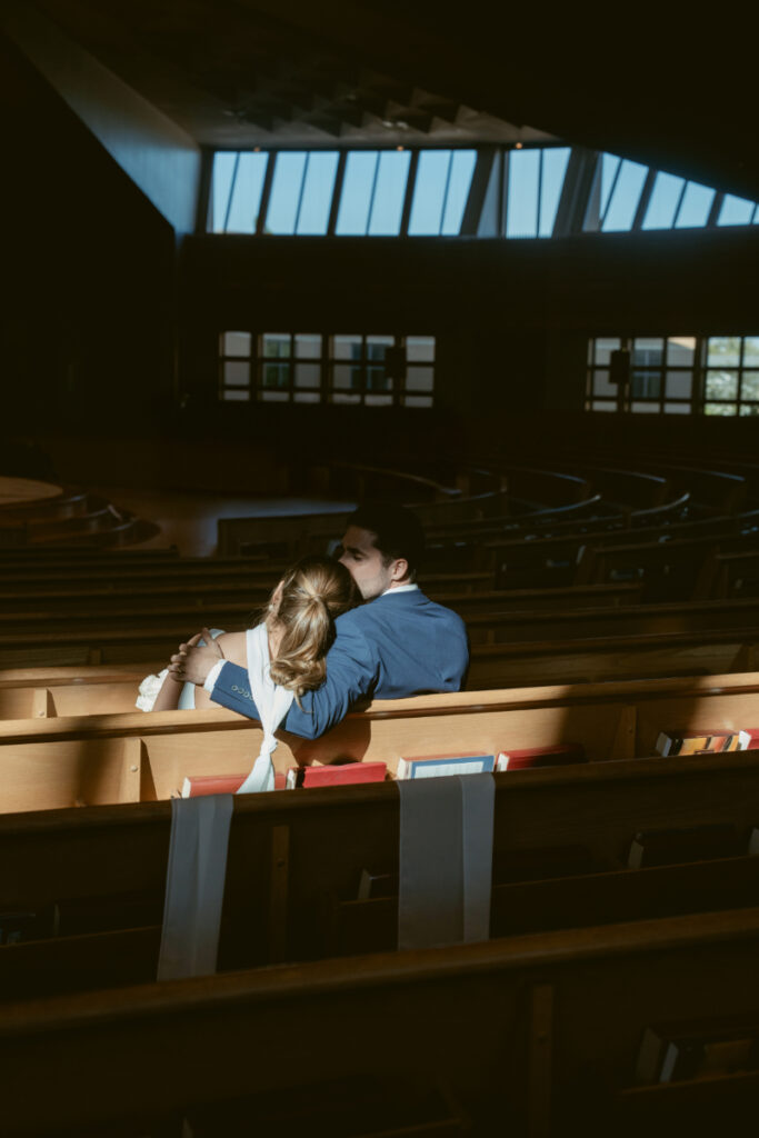 Bride and groom share a quiet moment in church pews before their Laurel Court wedding celebration.