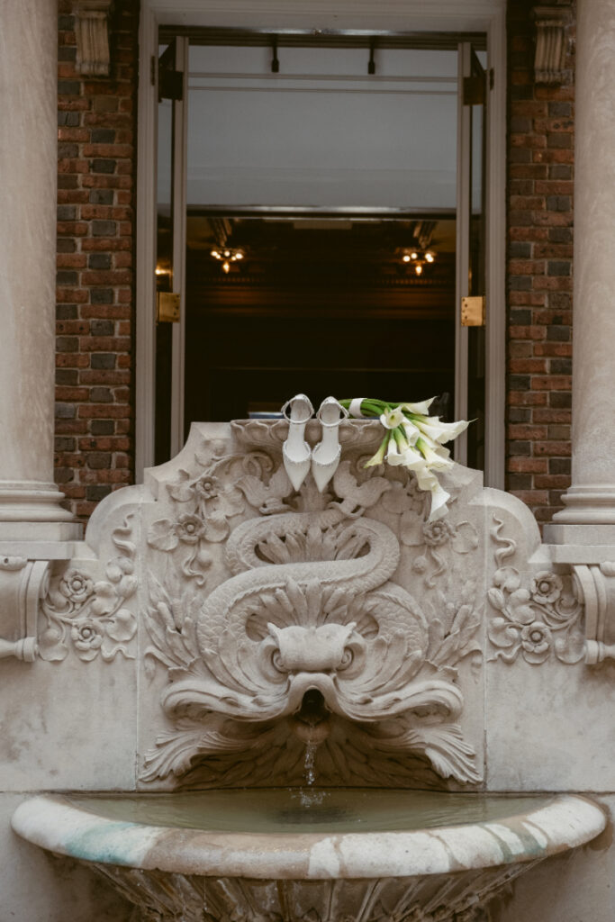 Bridal shoes and bouquet styled on ornate fountain during a Laurel Court wedding.