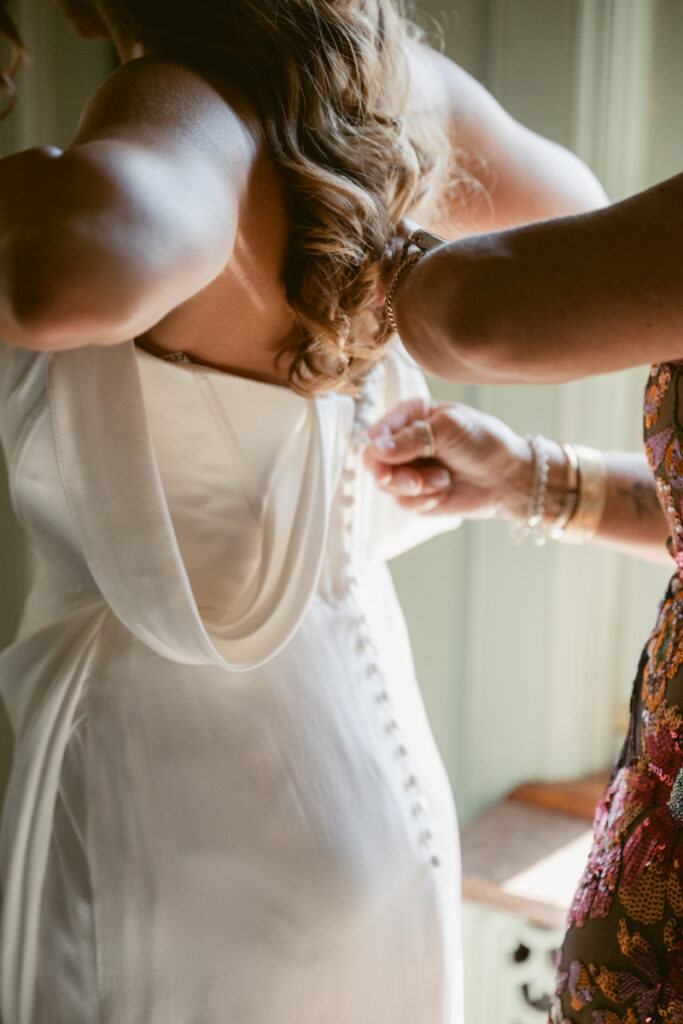 Bride getting buttoned into her dress during morning prep for a Laurel Court wedding.