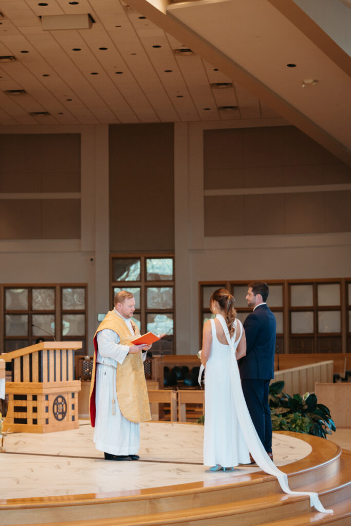 Bride and groom standing at the altar during their Catholic ceremony before their Laurel Court wedding.