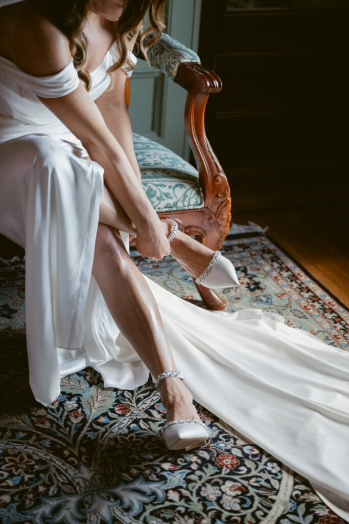 Bride putting on heels in vintage room while getting ready for her Laurel Court wedding.