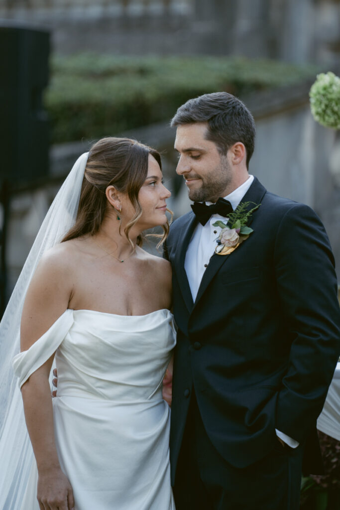 Bride and groom share an intimate moment, gazing at each other after their elegant outdoor ceremony.