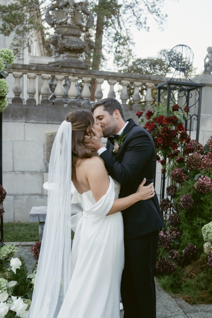 Bride and groom share their first kiss as a married couple during romantic outdoor wedding ceremony.