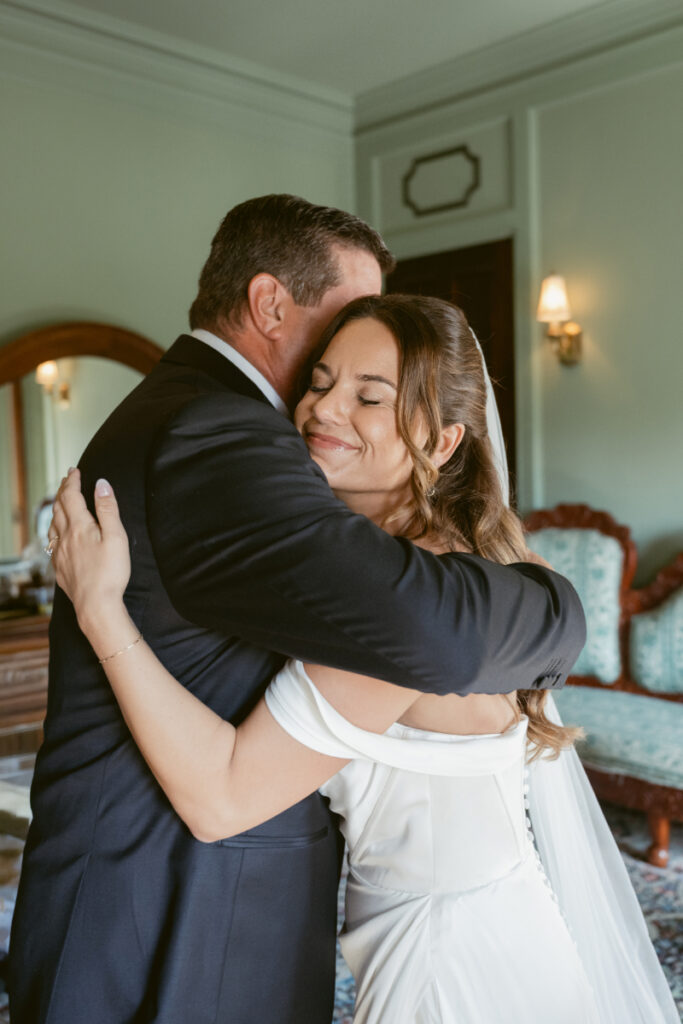 Bride hugging her father with a smile during a sweet first look at their Laurel Court wedding.