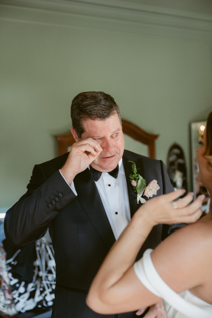 Emotional father wiping tears during first look with bride at their Laurel Court wedding.