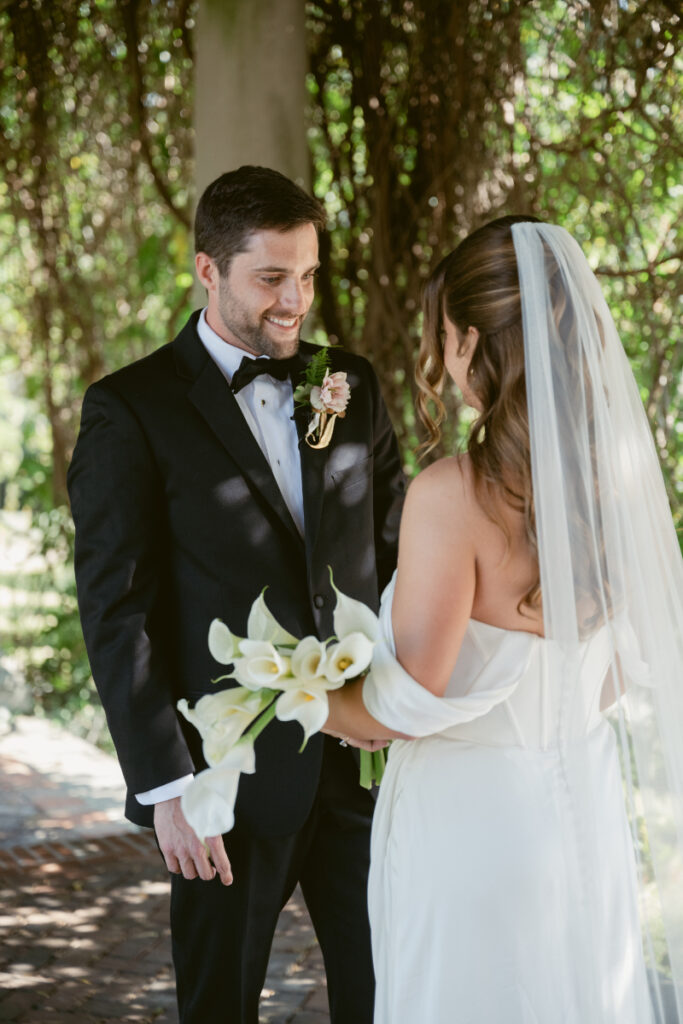 Bride and groom share a kiss under ivy-covered pergola during their Laurel Court wedding.