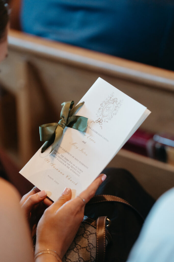 Wedding guest holding a ceremony program tied with ribbon during a Laurel Court wedding weekend.