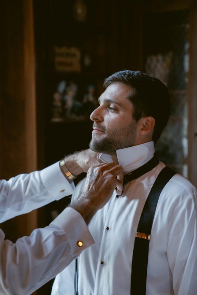 Groom getting help with his bow tie while getting ready for a Laurel Court wedding.