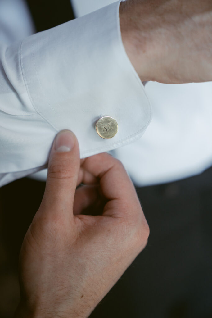 Groom fastening personalized cufflink while getting ready for his Laurel Court wedding.