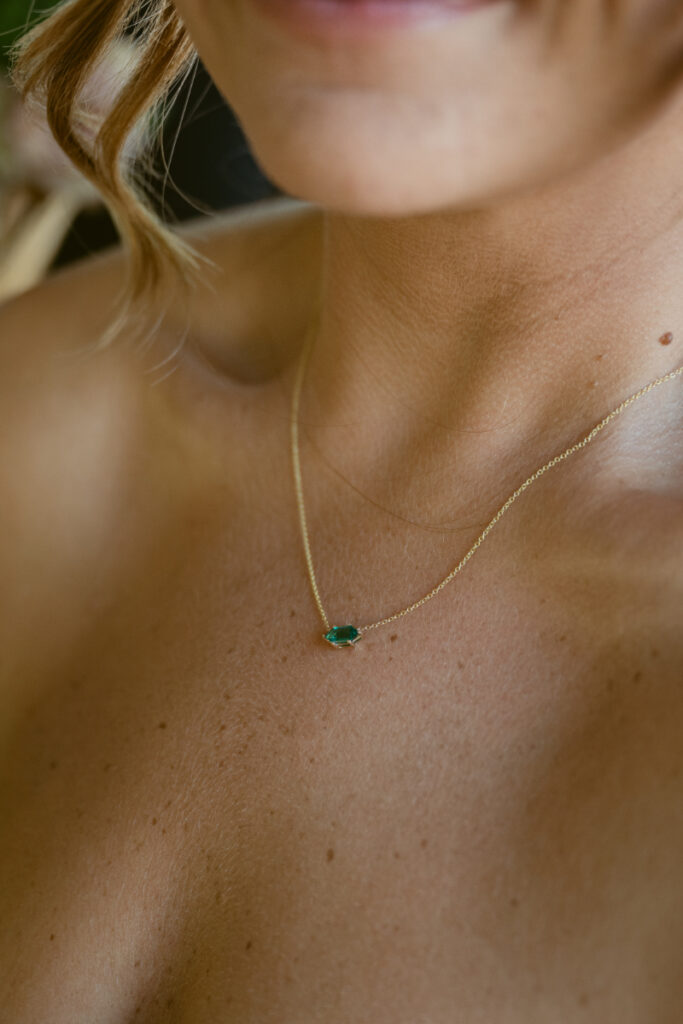 Close-up of bride’s emerald necklace, a delicate detail from her Laurel Court wedding look.