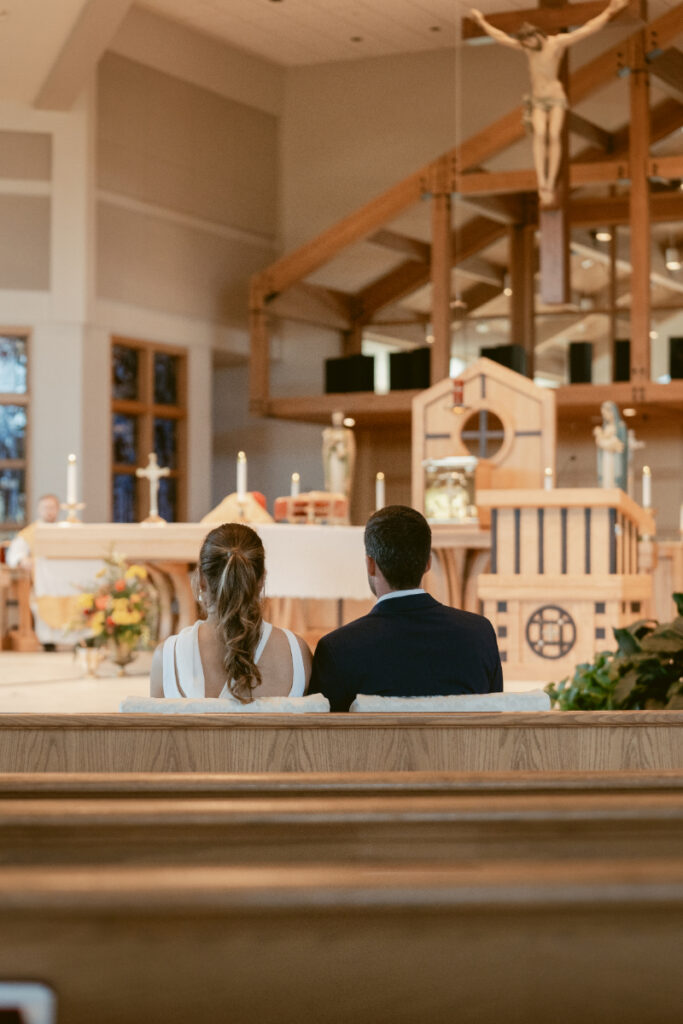 Bride and groom seated together during their Catholic ceremony before their Laurel Court wedding.