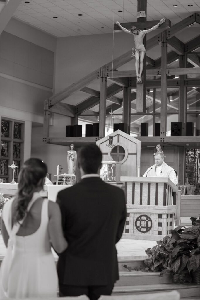 Bride and groom standing before the altar during Catholic ceremony ahead of their Laurel Court wedding.