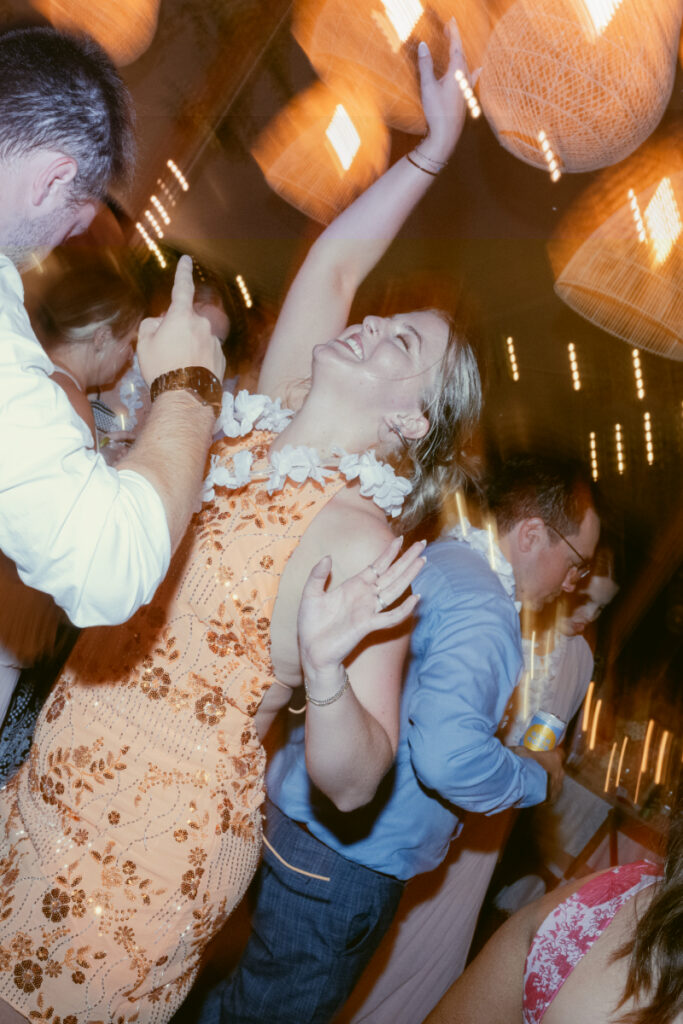 Guest throws her arm up mid-dance, glowing with energy under warm lights and celebration all around.