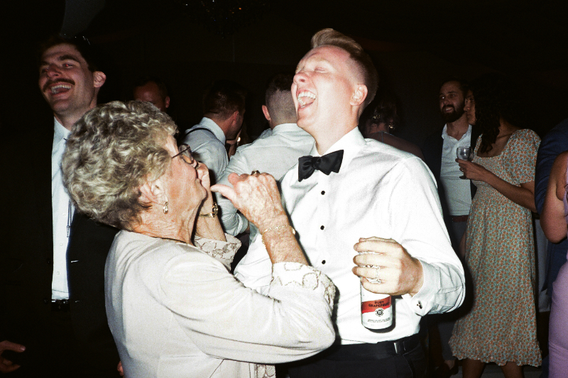 A joyful guest bursts into laughter while dancing with his grandmother—pure celebration and unforgettable connection.