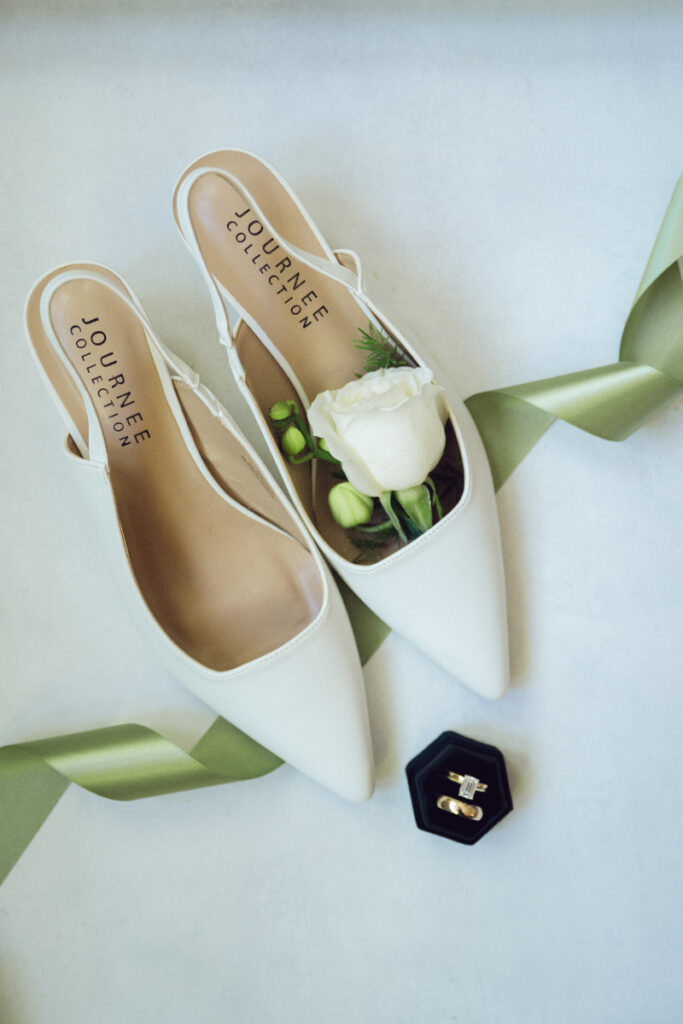Flat lay of wedding shoes, rings, and florals—perfect details for couples who just got engaged.