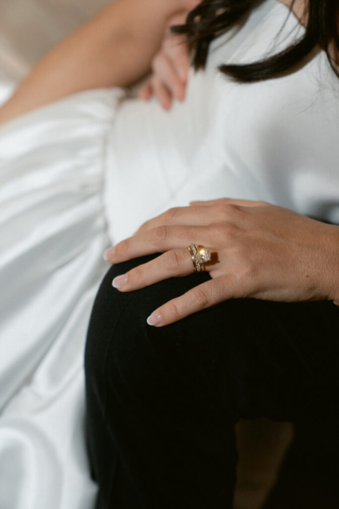 A close-up of the bride’s hand shows her elegant gold wedding ring against her gown.
