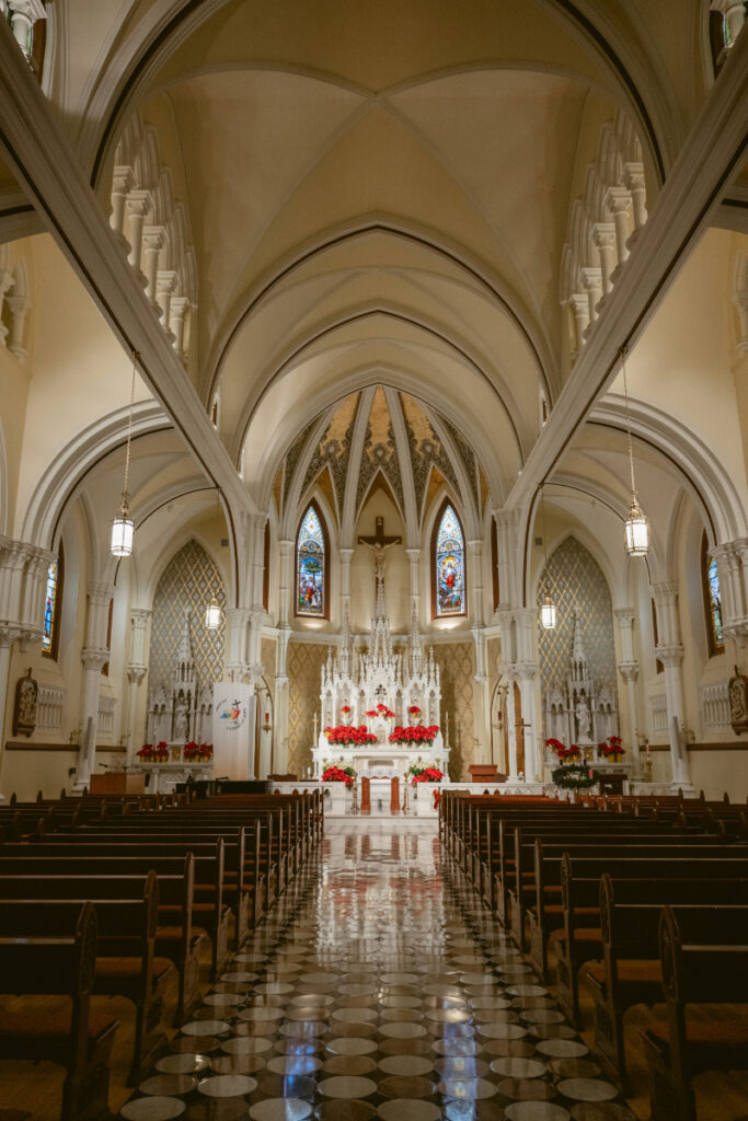 Stunning cathedral interior decorated with red florals, ready for a romantic Christmas wedding ceremony.