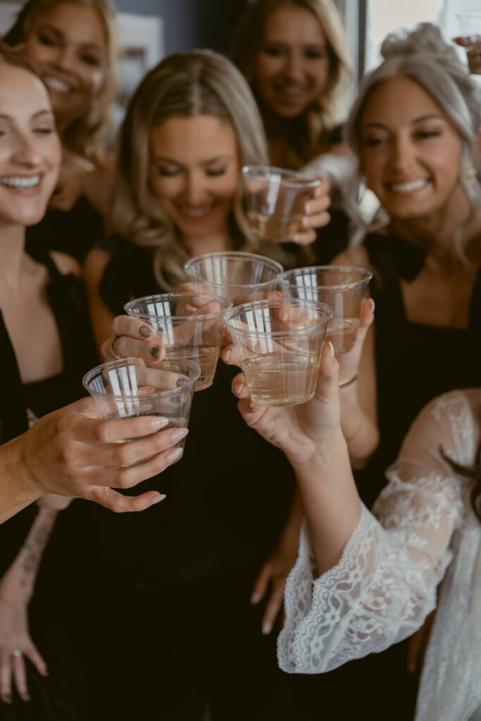 Bride and bridesmaids toasting with champagne before cozy Christmas wedding, wearing robes and pajamas.
