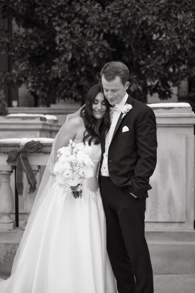 Bride and groom share a quiet moment together, smiling softly in a black and white portrait.