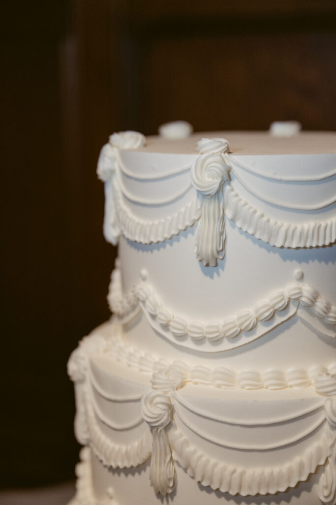 Elegant white wedding cake with piped ribbon details, perfect for a cozy Christmas wedding celebration.