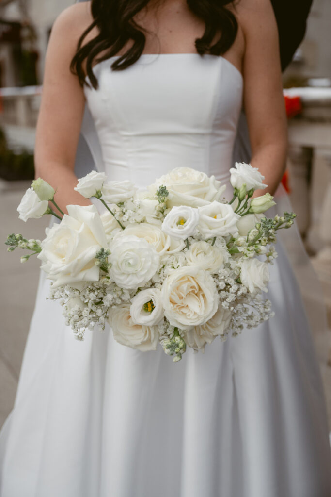Close-up of the bride’s white rose bouquet, filled with ranunculus, lisianthus, and baby’s breath.