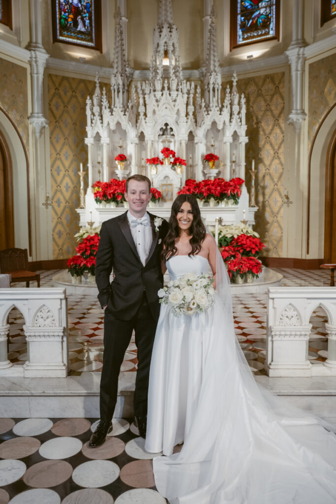 bride and groom pose for a photo with poinsettias in the background
