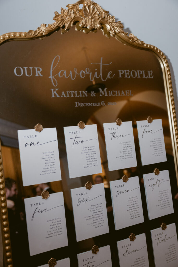 Gold-framed mirror seating chart with wax-sealed cards for a cozy Christmas wedding reception.