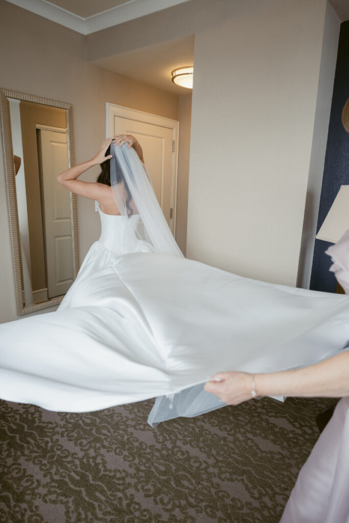 Bride adjusting veil in hotel room mirror before cozy Christmas wedding in downtown Cincinnati