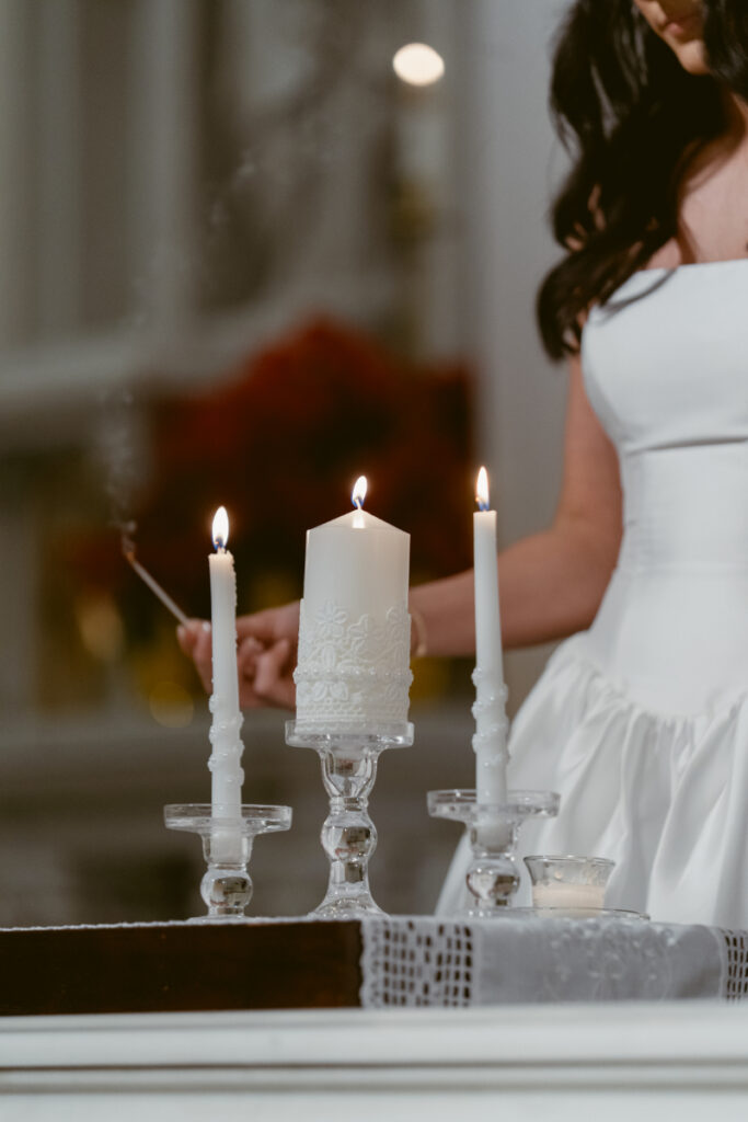 bride lighting candles during wedding ceremony in a church