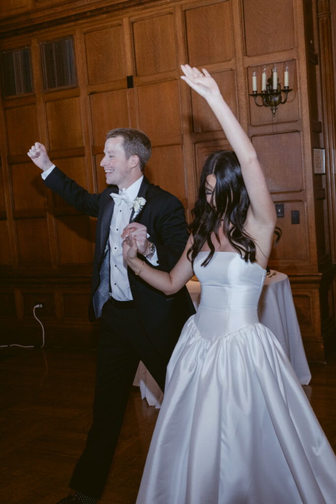 bride and groom walking into their wedding happy with their hands in the air 
