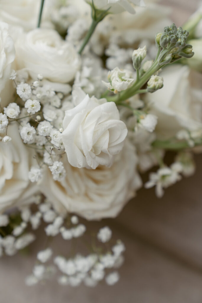 Close-up of white roses and baby's breath in bride's bouquet with soft natural lighting.