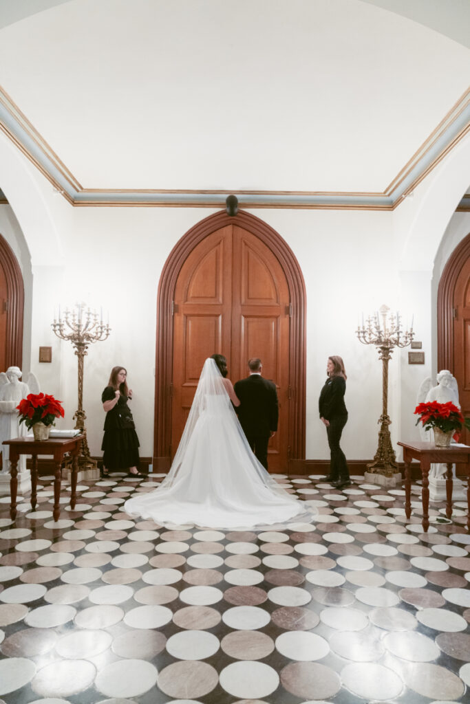 The bride waits with her father before walking down the aisle at her Christmas wedding ceremony.