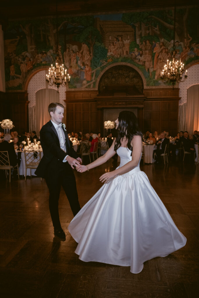 he bride twirls in her satin gown as the groom spins her during their joyful first dance.