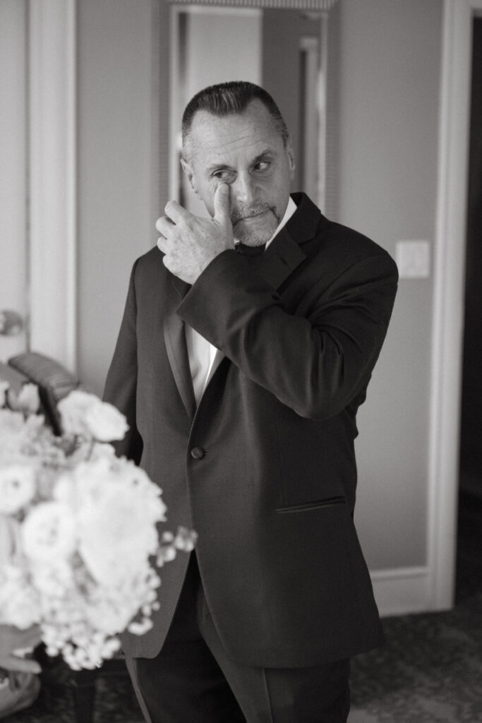 Emotional father wipes away a tear during first look at bride on cozy Christmas wedding morning.