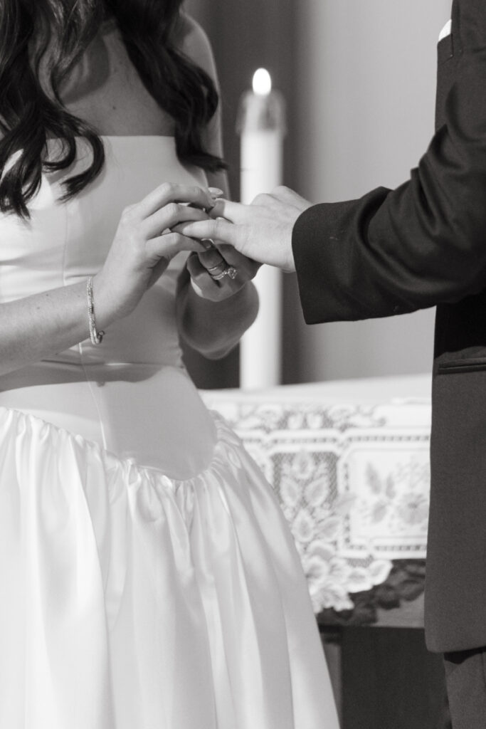 close up black and white photo of a bride placine a ring on the groom's finger