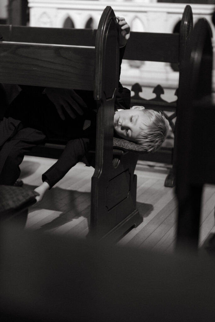 black and hite photo of a young boy sleeping on the bench at a cozy Christmas wedding 