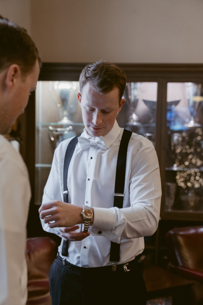 Groom adjusting watch while getting ready for his cozy Christmas wedding at the Cincinnati Athletic Club.