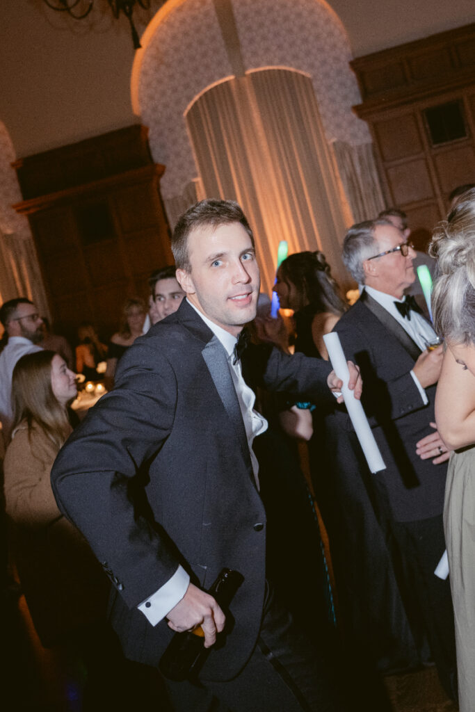 A guest dances confidently with glow sticks during the lively wedding reception.