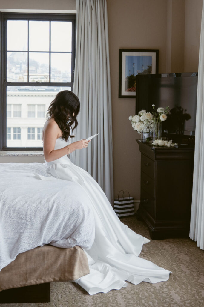 Bride reading a letter by the window before her cozy Christmas wedding in downtown Cincinnati.