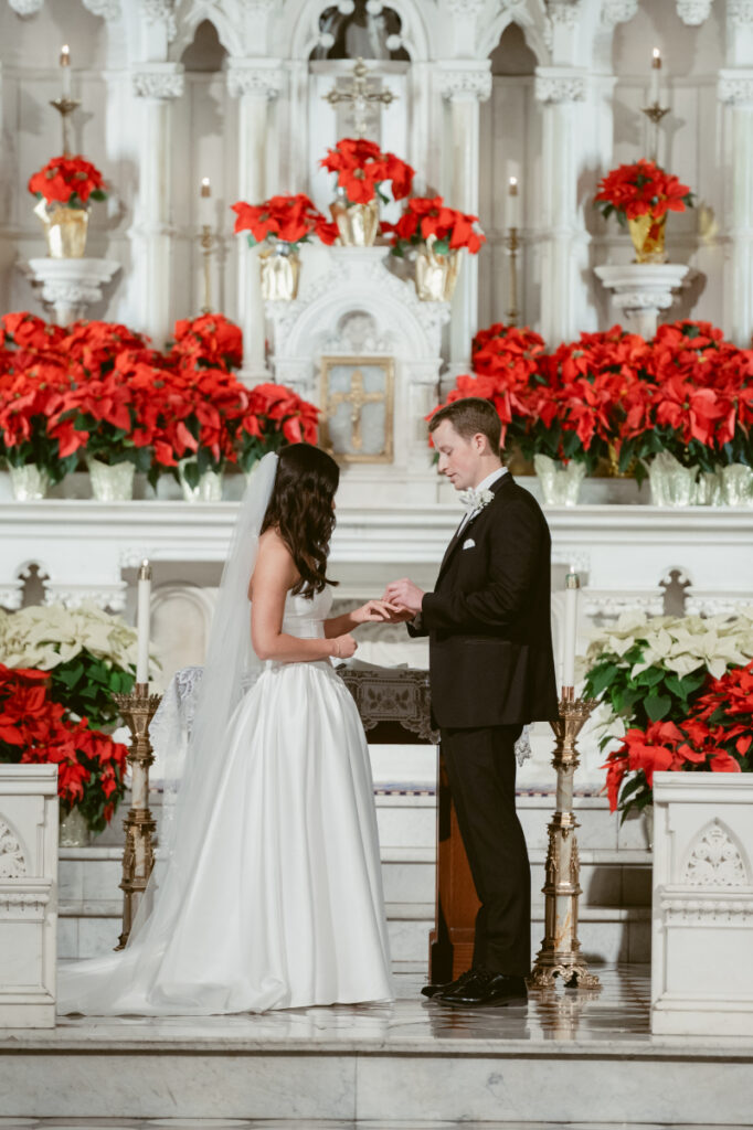 groom placing a ring on the brides hand at a cozy Christmas wedding 