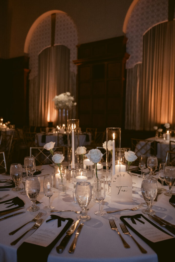 Elegant winter wedding table setup with candlelight, white roses, and black accents.