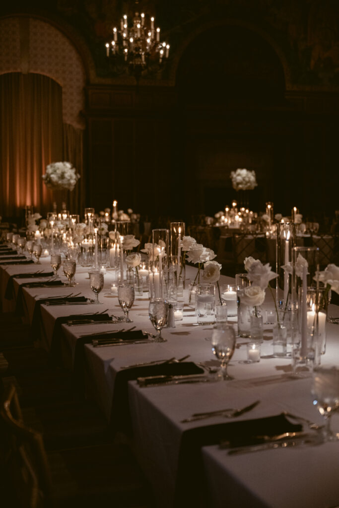 Elegant candlelit reception tables with white roses set the scene for a cozy Christmas wedding.