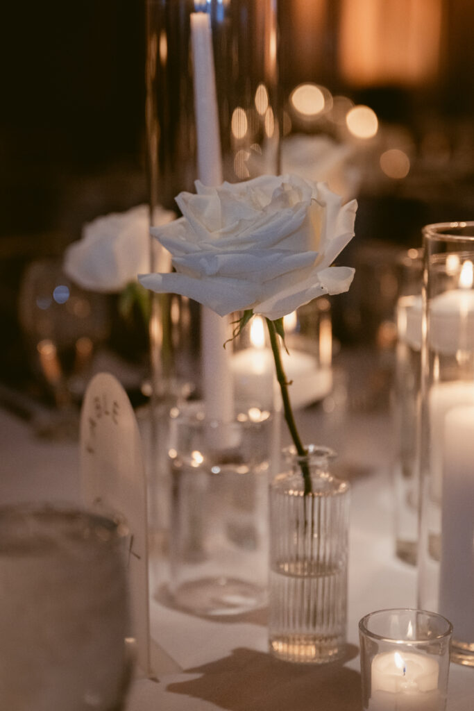 Single white rose and candlelight add a romantic touch to this cozy Christmas wedding table.