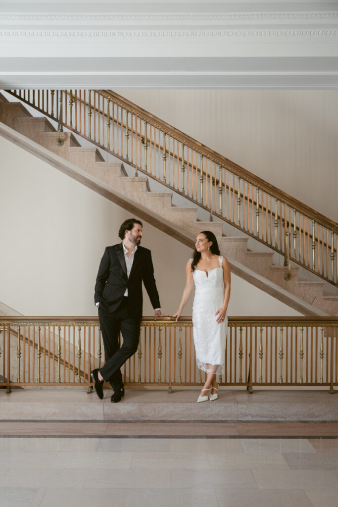 Bride and groom holding hands on courthouse stairs during Valentine’s Day wedding.