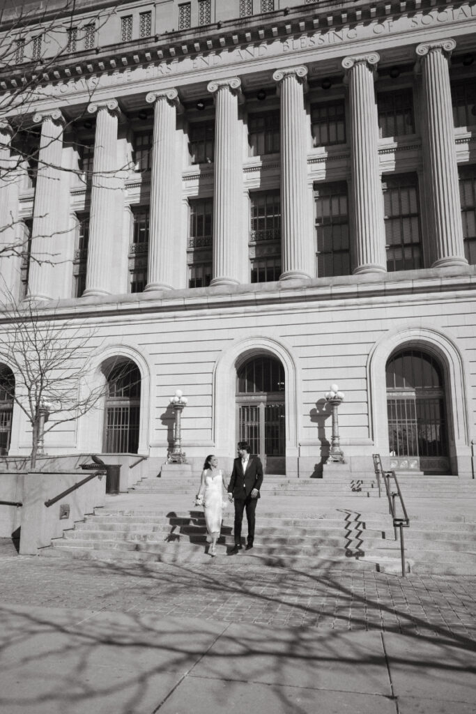 Couple walking on courthouse steps during downtown Valentine’s Day wedding.