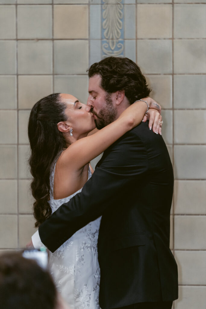 Bride and groom sharing first kiss at their Valentine’s Day wedding ceremony.