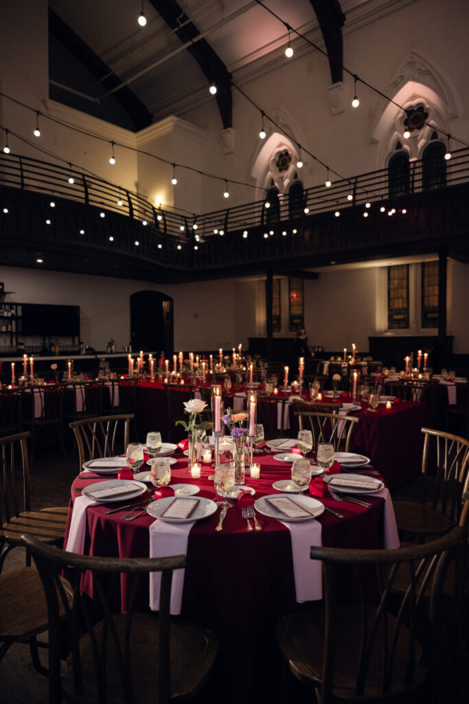 Reception space with red table linens and candlelit decor.