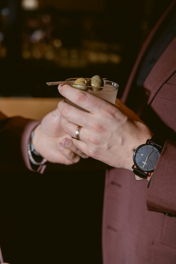 Groom adjusting cufflinks and wedding band during evening reception.