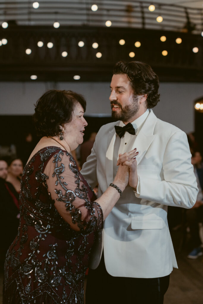 Groom dancing with family member during wedding reception.
